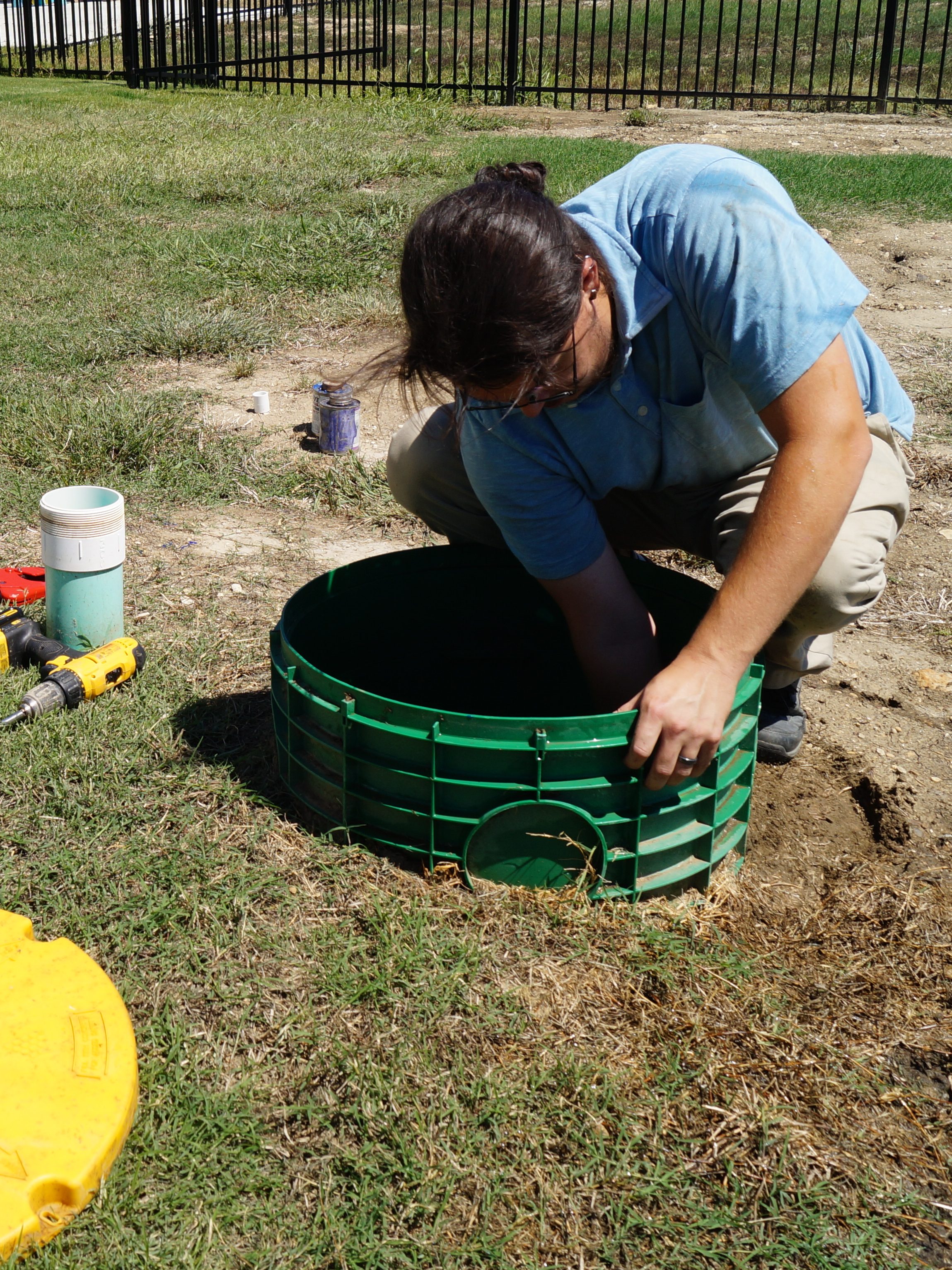 A man reaches into a septic riser for an inspection.