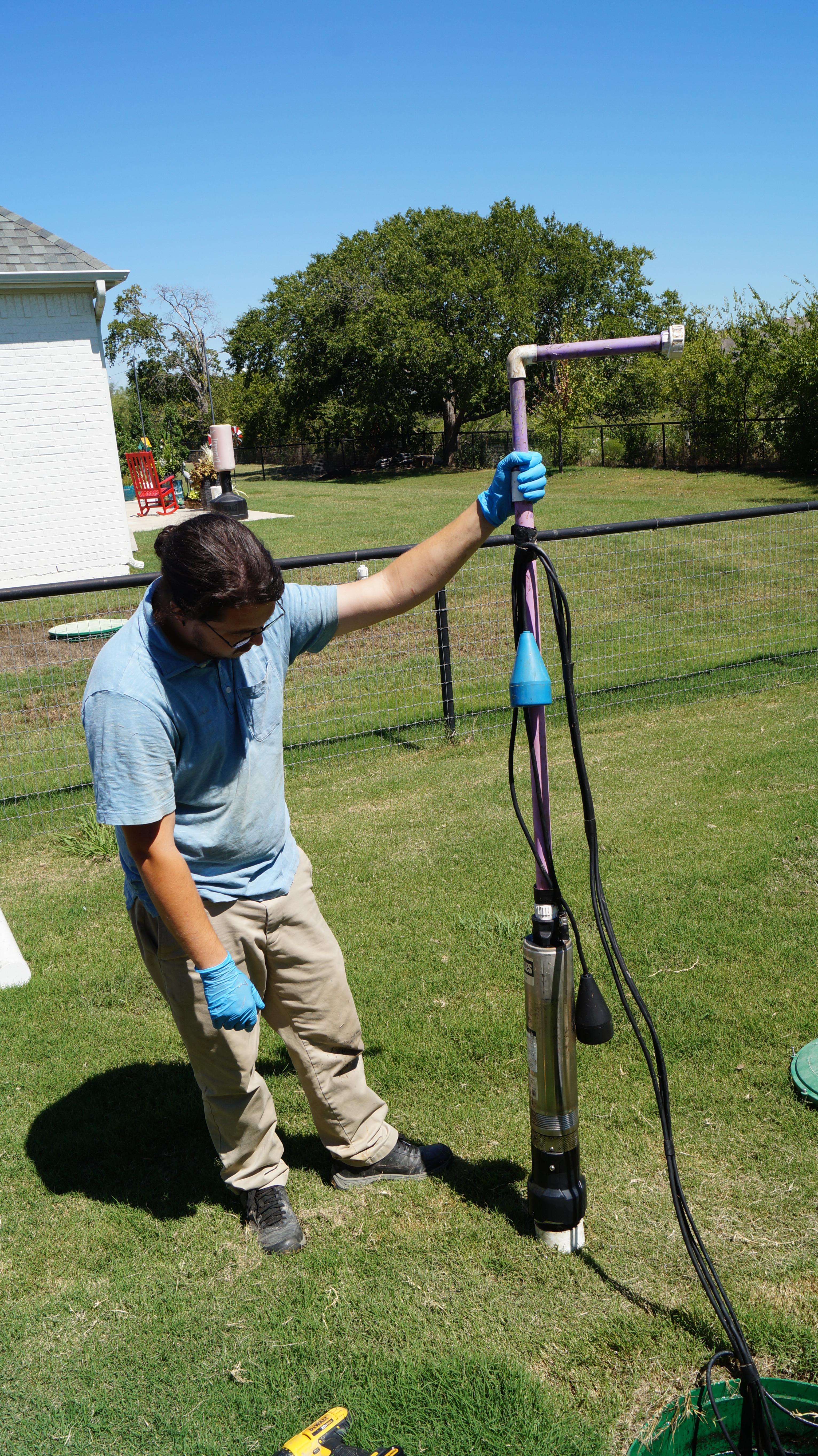 A technician visually inspects a septic pump that he has just removed from a septic tank.